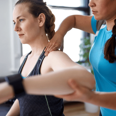 Therapist assists athlete’s arm movement and shoulder support, typical rehab at sports injury clinic