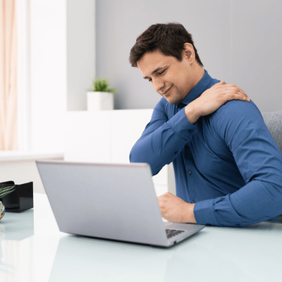Man touches shoulder in pain while working, possibly needing rotator cuff surgery recovery support.