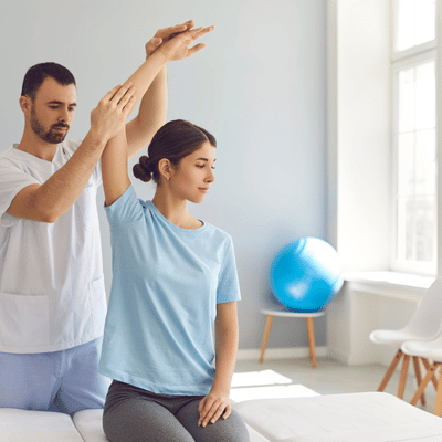 Female patient receives guided arm mobility exercise during rotator cuff surgery recovery in bright therapy room