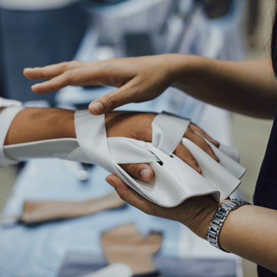 Photo shows provider fitting hand brace and straps, demonstrating sports injury clinic rehabilitation care