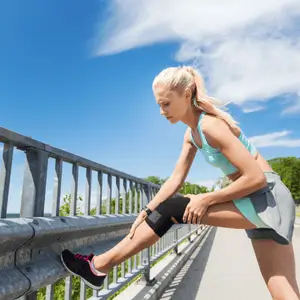 Woman stretches outdoors while continuing physical therapy after knee surgery to support athletic recovery