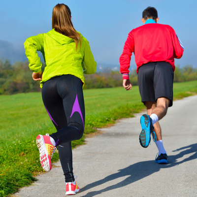 Two athletes jog outdoors on a paved path, using running as part of recovery training