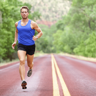 Athlete runs confidently on open road through greenery, showcasing recovery and improved movement after treatment