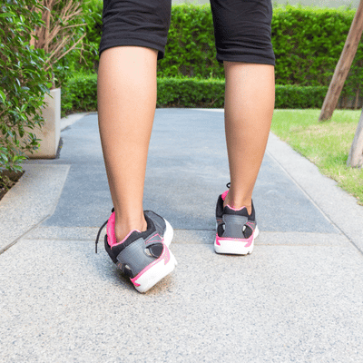 Person walking on paved path, recovering calf strength with sports medicine physical therapy guided exercise