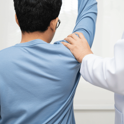 Clinician stabilizes patient’s shoulder while arm lifts, assessing movement and pain during orthopedic rehab visit