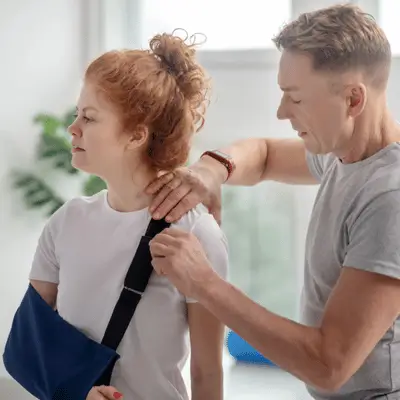 Therapist adjusts sling for woman recovering from shoulder injury after rotator cuff surgery recovery
