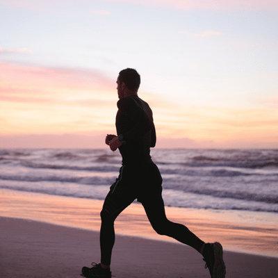 Runner training on beach at sunset after injury, supported by sports medicine physical therapy guidance